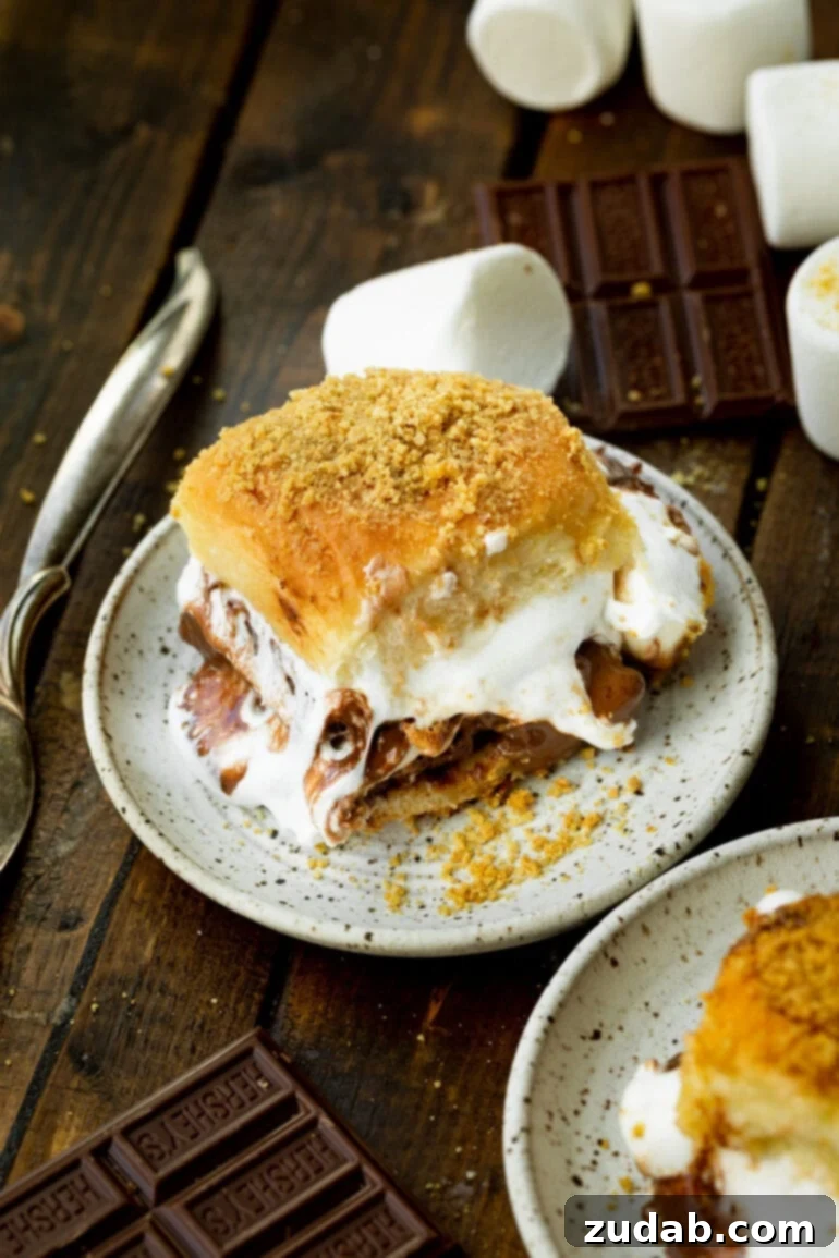 Gooey Smores Sliders 7 A perfectly baked, gooey s'mores slider rests on a small dessert plate, ready to be devoured, highlighting its warm, inviting texture.