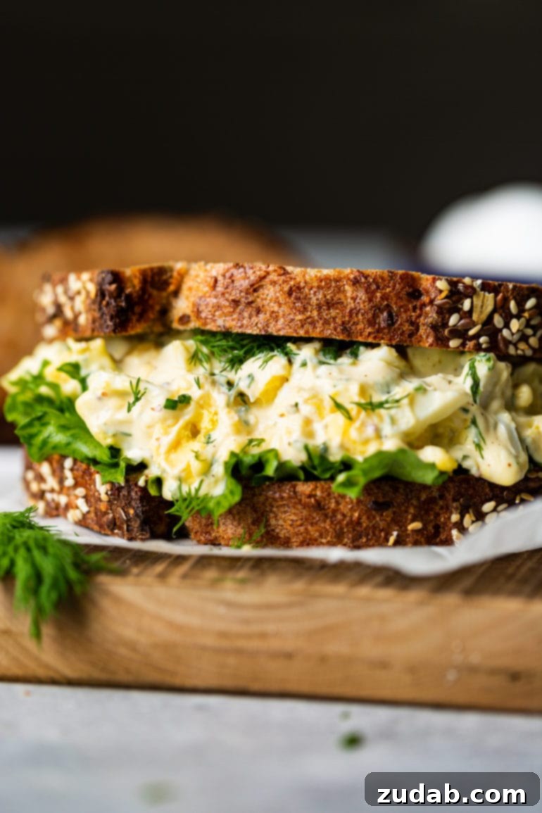 Weekly Menu Plan: April 1-7 5 a photo of an egg salad sitting on a piece of parchment paper made on multigrain bread with lettuce and thick layer of egg salad.