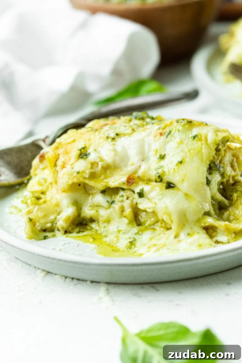 This Week's Menu: April 22-28 6 A delectable serving of creamy white chicken pesto lasagna, showcasing layers of pasta, rich béchamel sauce, vibrant green pesto, and melted cheese, ready to be enjoyed.