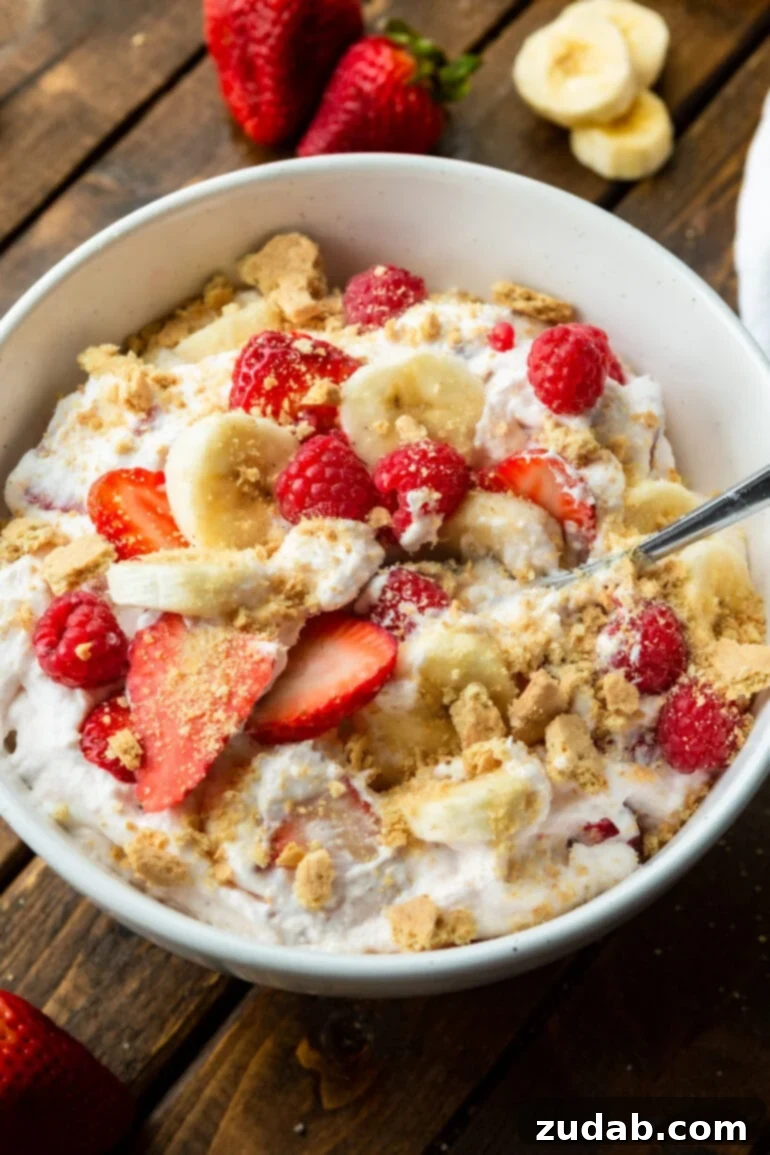 Fluffy Cheesecake Fruit Salad 8 a photo of a bowl of creamy cheesecake fruit salad with crumbled graham crackers with sliced strawberries and bananas.