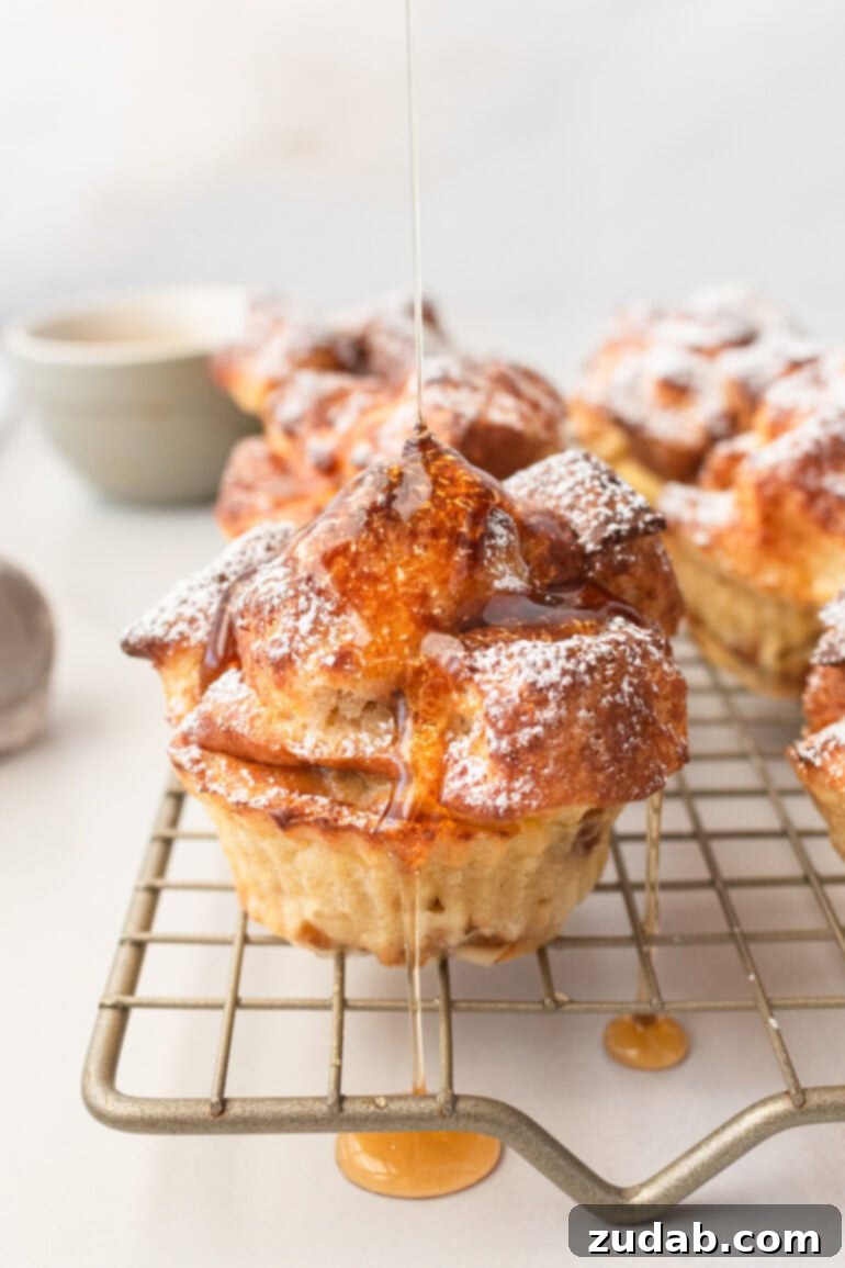 a photo of several golden air fried french toast muffins topped with powder sugar and drizzled with maple syrup