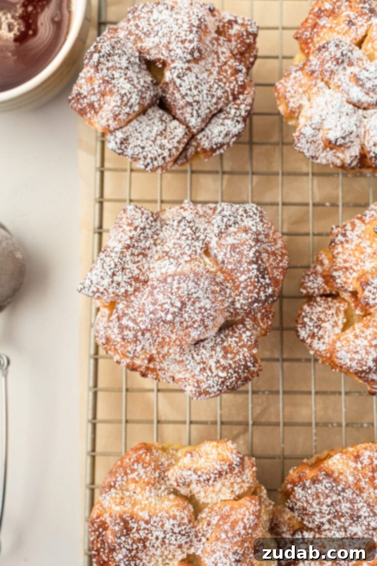a photo taken over the top of several baked french toast muffins dusted with powdered sugar and sitting on a wire cooling rack