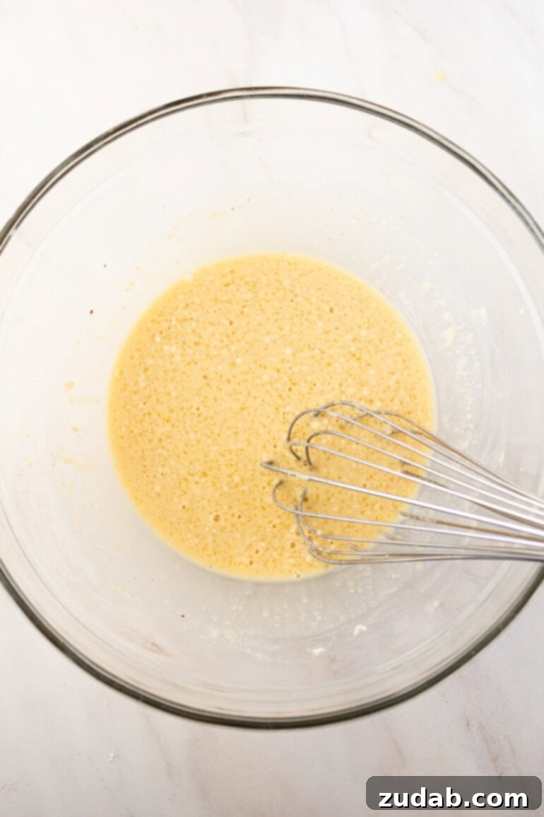 Step-by-step image of adding dry ingredients to wet mixture for Air Fryer French Toast Muffins