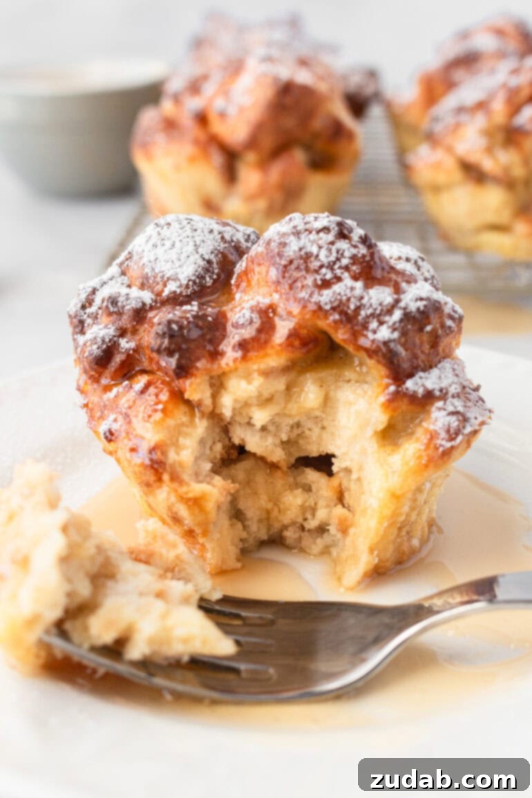 a photo of a golden baked french toast muffin with a bite taken out of it so you can see the soft and fluffy inside