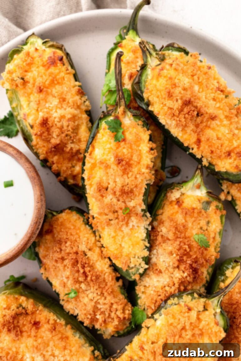 Effortless Air Fryer Jalapeño Poppers 11 A photo of golden crispy jalapeno poppers with a small cup of garlic dip sitting next to it