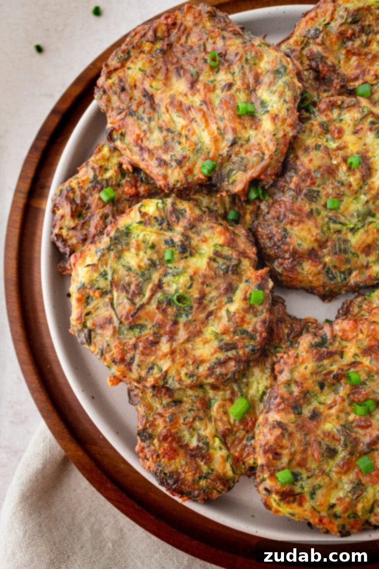 a photo of several crispy golden zucchini fritters sitting on a serving plate