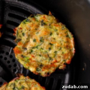 a photo of several golden fried zucchini fritters sitting next to a small cup of creamy dipping sauce