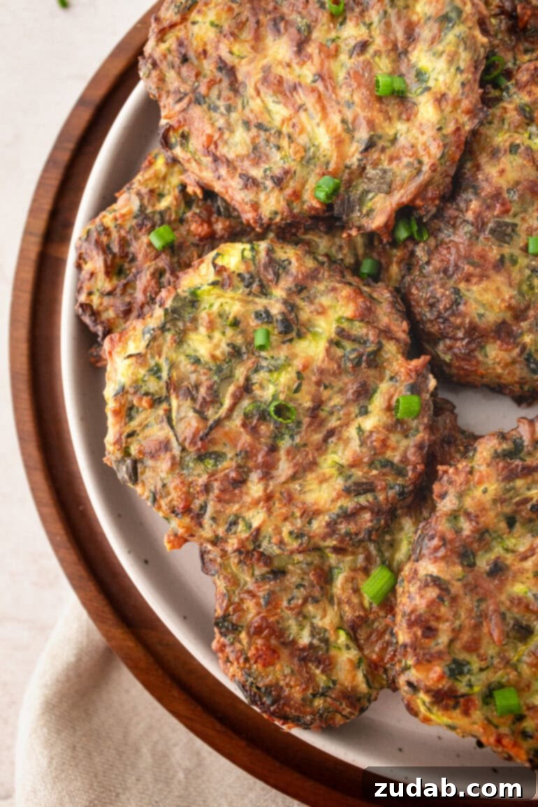 a photo of a large serving plate filled with crispy golden zucchini fritters