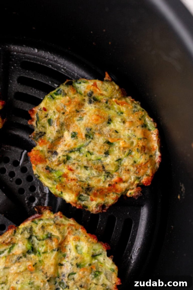 a photo of  zucchini fritters sitting in an air fryer basket