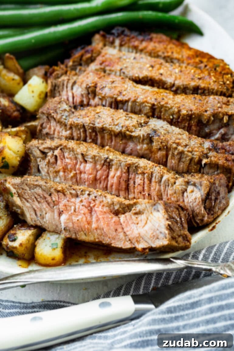 Perfect Air Fryer Steak with Garlic Butter 2 a photo of several strips of ribeye steak on a plate with roasted cubed potatoes and cooked fresh green beans