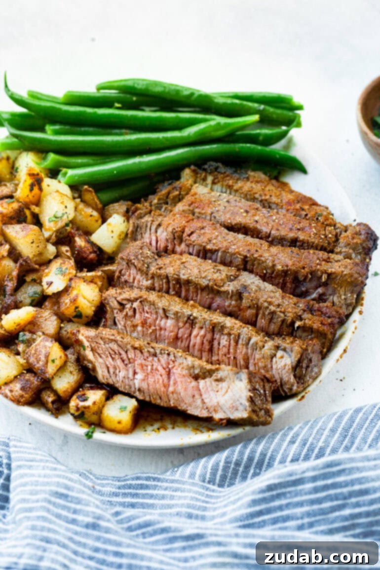 Perfect Air Fryer Steak with Garlic Butter 3 a photo of a tender steak that has been sliced into strips with a side of cubed roasted potatoes and cooked fresh green beans