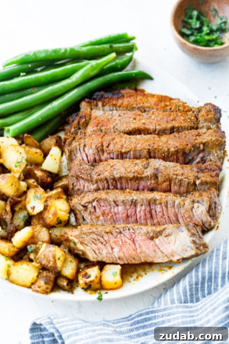 Perfect Air Fryer Steak with Garlic Butter 4 a photo of a plate of sliced steak with roasted potatoes and cooked green beans.