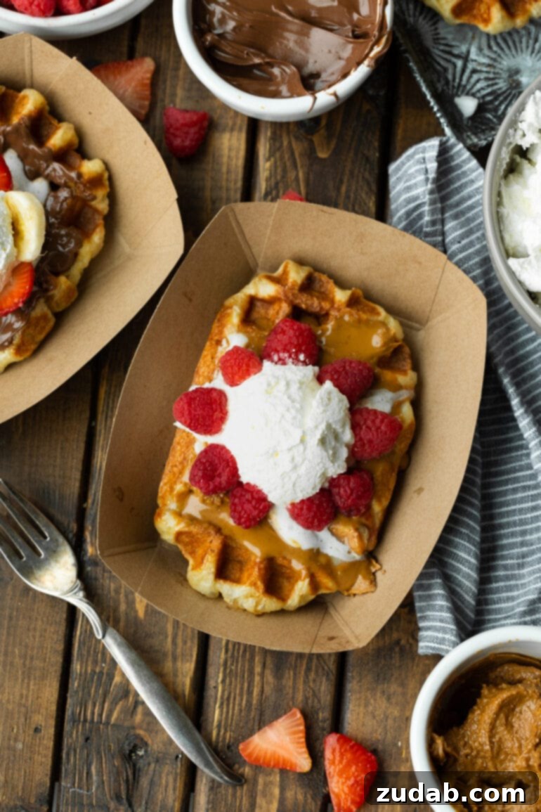 Mastering Waffle Love's Signature Liege Waffles 10 A photo of a Liege waffle in a brown cardboard container topped with Biscoff cookie butter, fresh raspberries, and a scoop of whipped cream. A perfect single serving of Waffle Love.