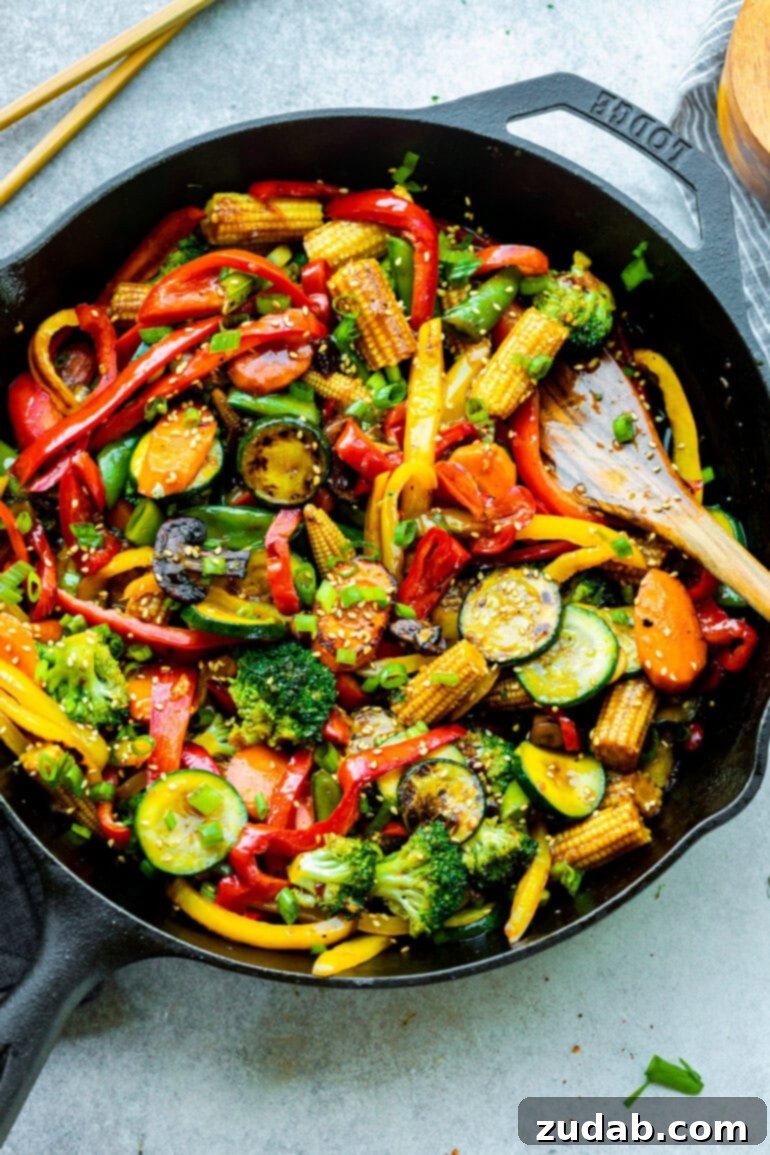 My Go-To Speedy Veggie Stir-Fry 5 A large cast iron skillet filled with a colorful and fragrant vegetable stir fry, with a wooden spoon resting on the side, ready to serve.
