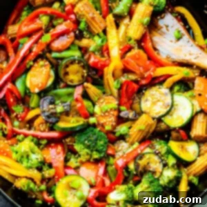 A vibrant and colorful vegetable stir fry, brimming with fresh ingredients, served in a large cast iron skillet.