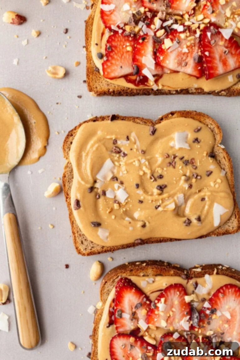 Creamy Coconut Peanut Bliss 11 A photo of several slices of multigrain toast topped with creamy coconut peanut butter, some garnished with sliced strawberries.