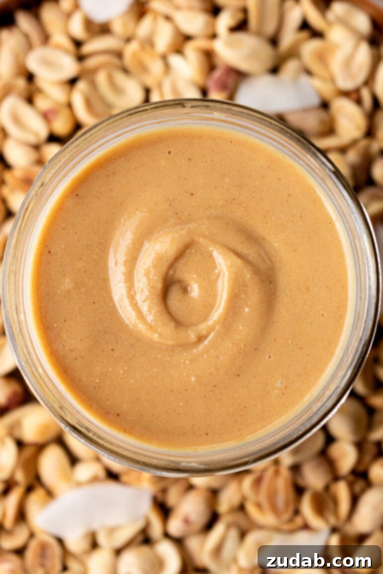 Creamy Coconut Peanut Bliss 12 A photo taken over the top of a glass jar full of creamy peanut butter with coconut, showcasing its inviting texture.