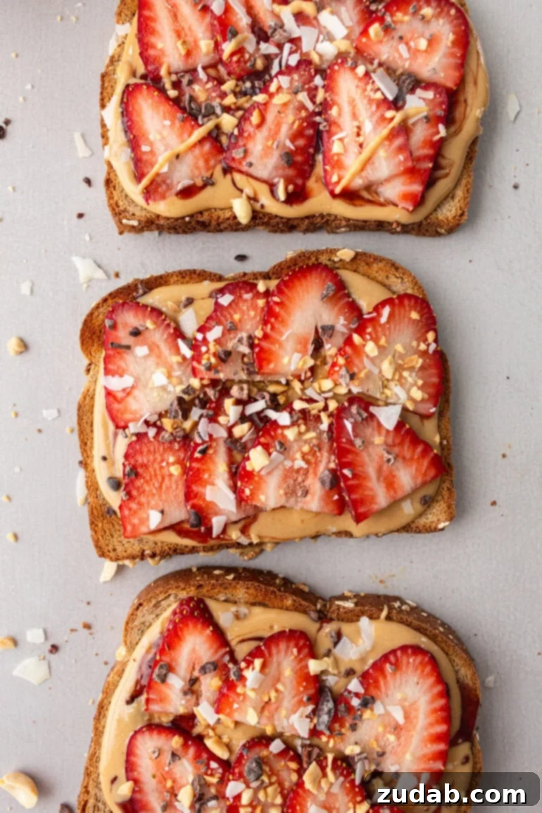 Creamy Coconut Peanut Bliss 4 A photo of three slices of whole grain toast topped with creamy coconut peanut butter, sliced strawberries, and a sprinkle of granola.