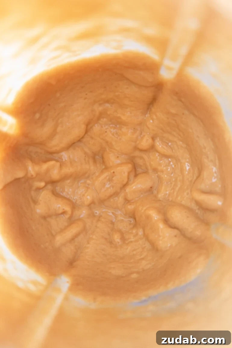 Creamy Coconut Peanut Bliss 6 A mid-stage photo showing the mixture of coconut and peanuts in the blender, transitioning from grainy to a thicker paste.