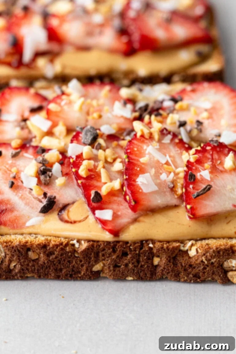 Creamy Coconut Peanut Bliss 8 A photo of a piece of multigrain toast topped with coconut peanut butter, sliced strawberries, and a sprinkle of granola.