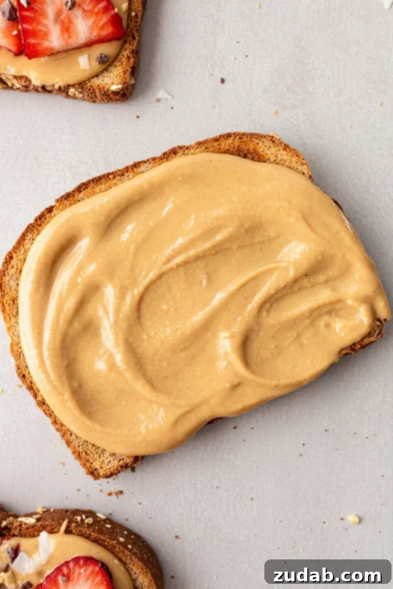 Creamy Coconut Peanut Bliss 9 A photo of a piece of toast generously covered with creamy coconut peanut butter, highlighting its smooth texture.