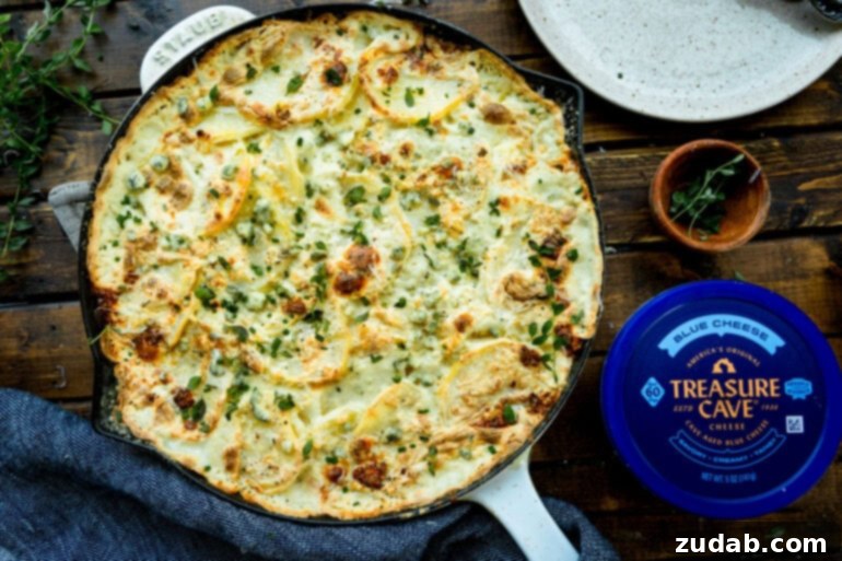 Decadent Blue Cheese Potato Gratin 11 A large skillet of golden-baked blue cheese scalloped potatoes, perfectly crusted, with a container of Treasure Cave Blue Cheese on the side.