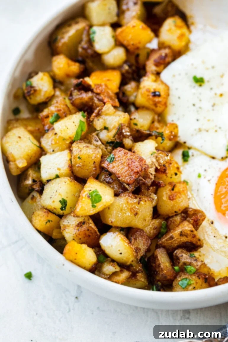 Ultimate Home Fries Recipe 2 A photo of golden crispy home fries on a plate next to two perfectly fried eggs, evoking a classic diner breakfast feel. Ideal for a savory breakfast or as a versatile potato side dish.