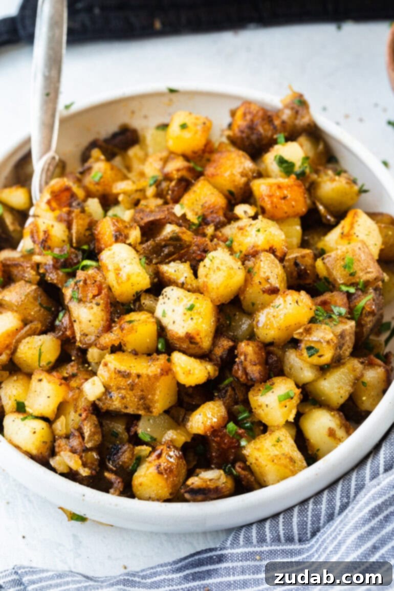 Ultimate Home Fries Recipe 5 A photo of a large white serving bowl filled with golden, crispy cubed potatoes, glistening and perfectly seasoned, a testament to proper cooking technique.