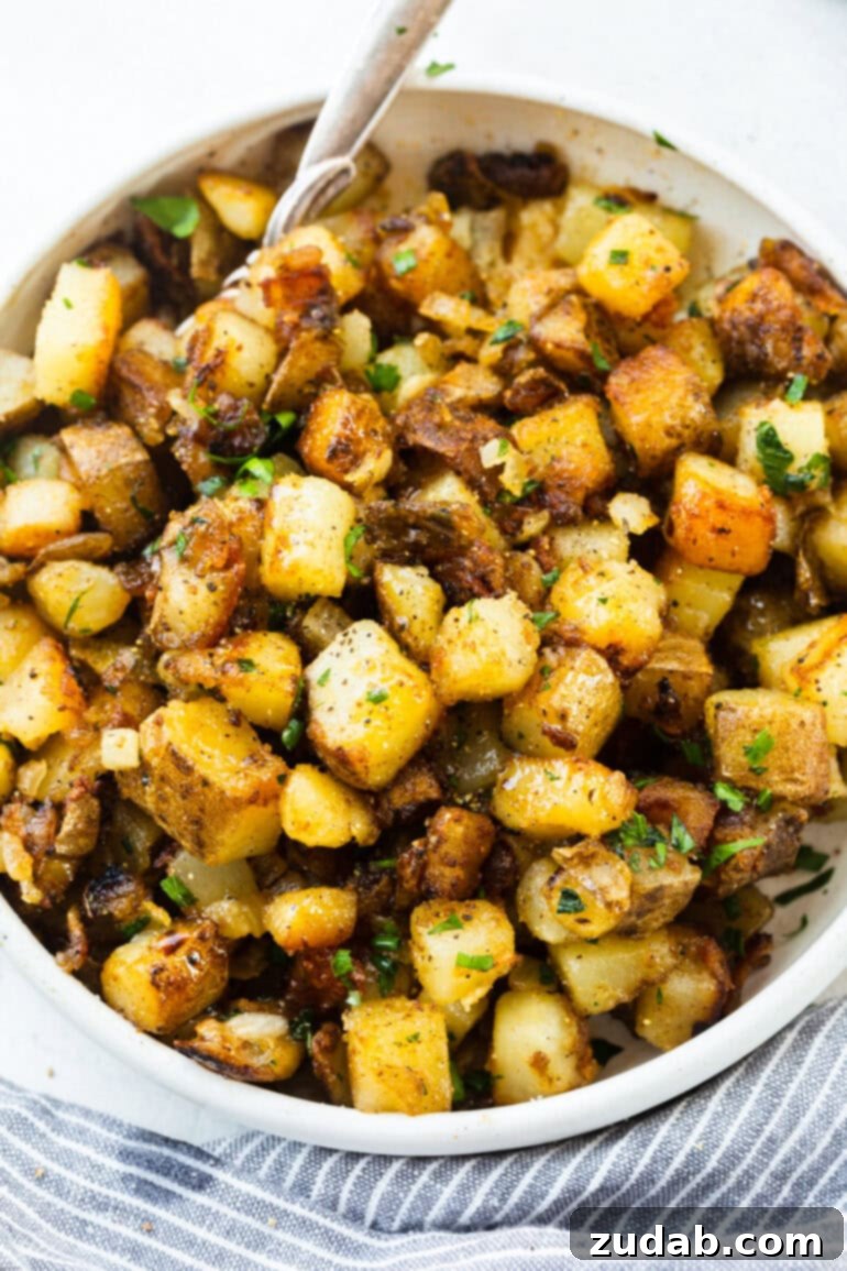 Ultimate Home Fries Recipe 7 A photo of cubed golden, crispy potatoes seasoned with salt, pepper, and fresh parsley, presented beautifully in a serving bowl.