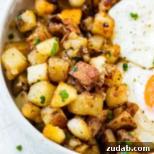 A photo of golden crispy home fries on a plate next to two fried eggs