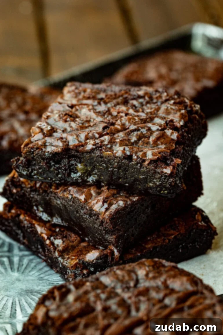 Elevated Box Brownies 2 A stack of three incredibly fudgy homemade chocolate brownies, showcasing their perfect texture and a delightful crinkle top.
