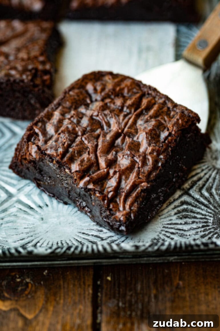 Elevated Box Brownies 5 A close-up of a delectable corner piece of a homemade chocolate brownie, showing off its rich, dark color and dense, moist interior.