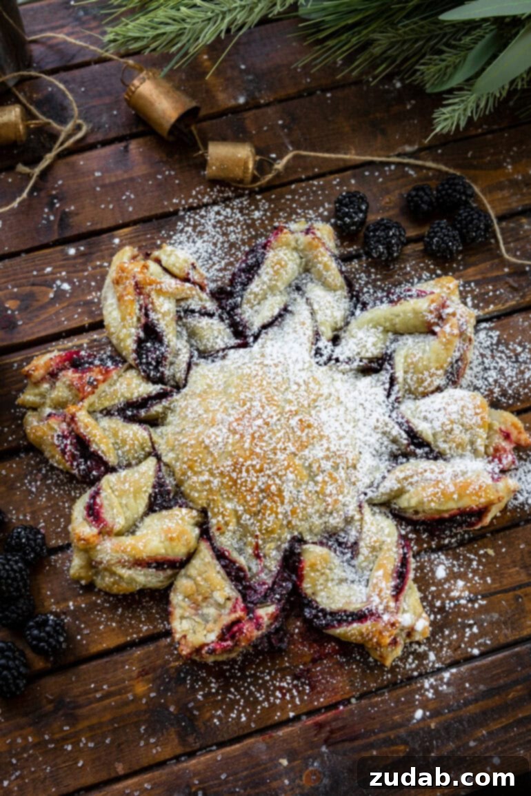 Blackberry Snowflake Puff Pastry 3 An overhead view of a freshly baked puff pastry snowflake, generously filled with a dark, glistening blackberry mixture, ready to be dusted with powdered sugar.