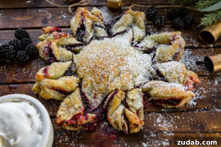 Blackberry Snowflake Puff Pastry 4 An inviting overhead shot of a golden-baked blackberry puff pastry snowflake, beautifully dusted with powdered sugar, ready for serving.