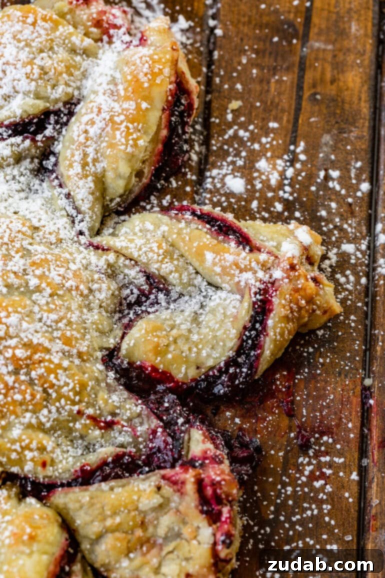 Blackberry Snowflake Puff Pastry 5 A close-up view of one intricate section of a baked blackberry puff pastry snowflake, showcasing its flaky layers and rich berry filling.