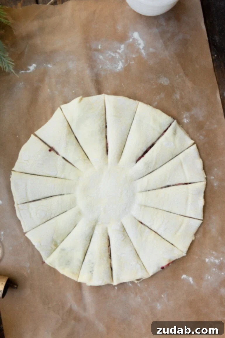 Blackberry Snowflake Puff Pastry 6 An unbaked puff pastry sheet, expertly cut into a perfect circle with a small central indentation and 16 radial strips cut from the center outwards, ready to be twisted into a snowflake design.