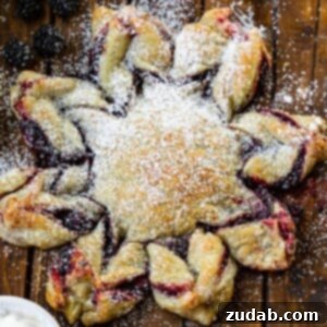 Blackberry Snowflake Puff Pastry 9 A top-down view of a golden-brown blackberry puff pastry snowflake, lightly dusted with powdered sugar, ready for serving.