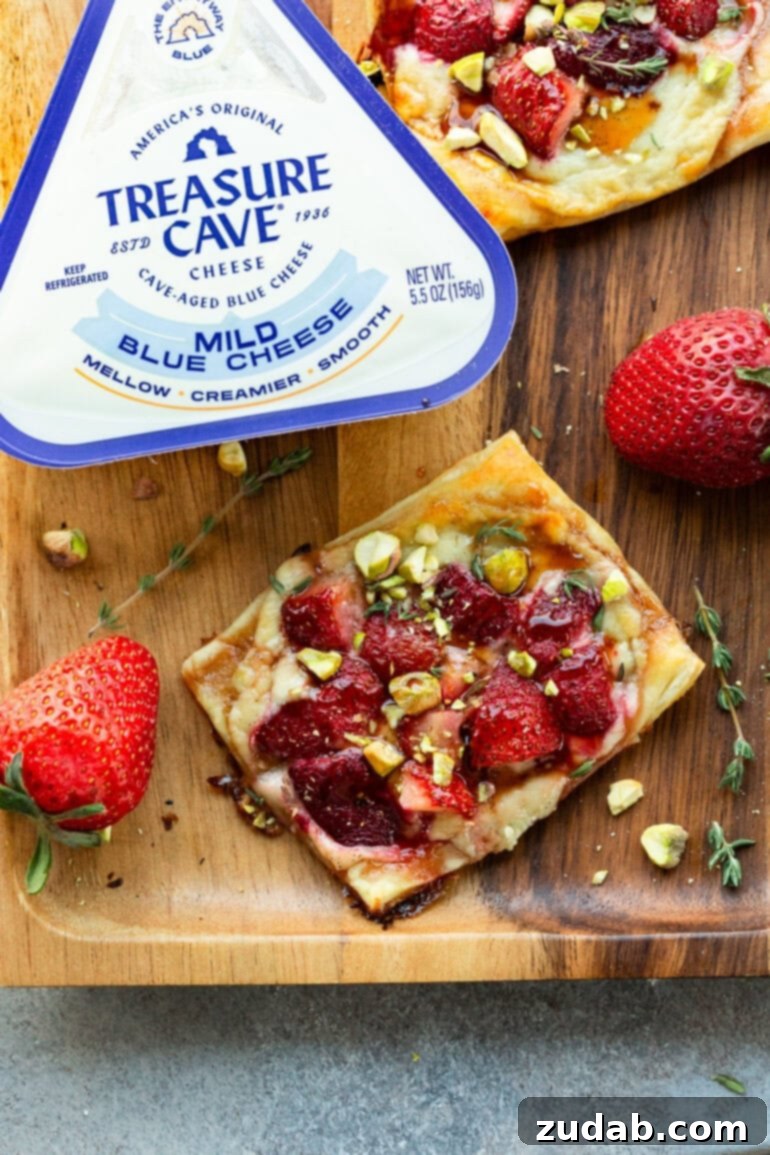 Effortlessly Gourmet Roasted Strawberry Blue Cheese Tarts 2 A beautifully golden-brown roasted strawberry tart resting beside a container of Treasure Cave Mild Blue Cheese, highlighting the key ingredients.