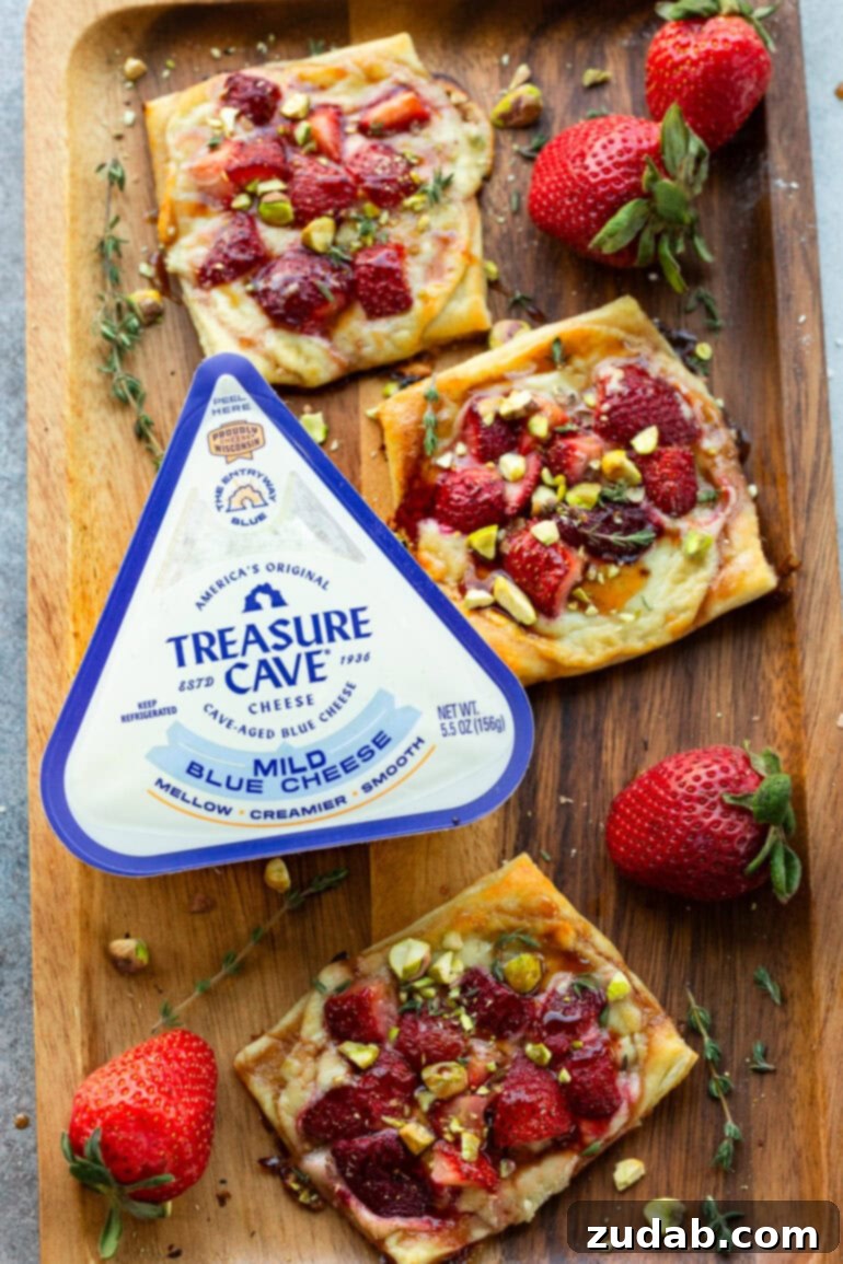 Effortlessly Gourmet Roasted Strawberry Blue Cheese Tarts 11 A platter showcasing several perfectly golden-baked roasted strawberry tarts, artfully garnished with blue cheese and pistachios.