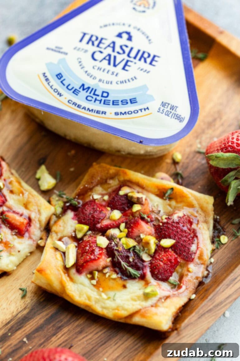 Effortlessly Gourmet Roasted Strawberry Blue Cheese Tarts 6 A roasted strawberry and blue cheese tart garnished with fresh thyme, with a package of Treasure Cave blue cheese subtly blurred in the background.
