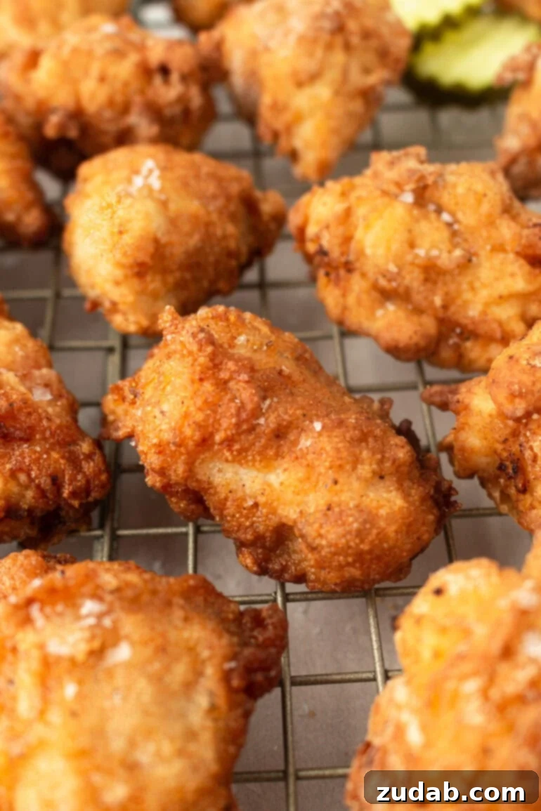 A photo of several perfectly golden and crispy homemade chicken nuggets cooling on a wire rack, ready to be served.
