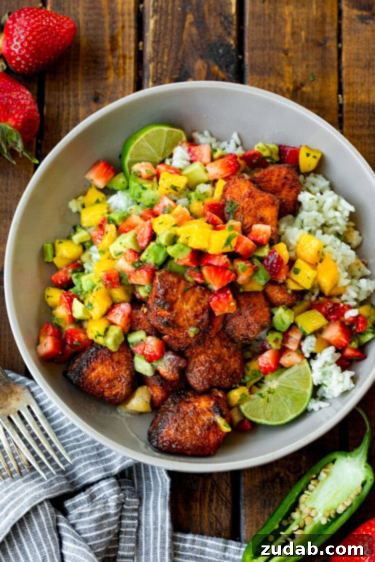 Golden Crispy 7-Minute Air Fryer Salmon Bites with Zesty Mango Salsa 11 A bowl of fluffy white rice crowned with perfectly seasoned, crispy salmon bites and a generous dollop of fresh mango salsa, creating a wholesome and appealing dish.