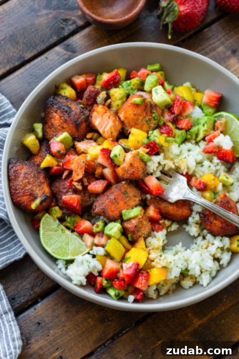 Golden Crispy 7-Minute Air Fryer Salmon Bites with Zesty Mango Salsa 12 A beautifully arranged coconut rice bowl, richly topped with golden crispy salmon bites and a generous serving of fresh mango salsa, presenting a wholesome and visually appealing meal.