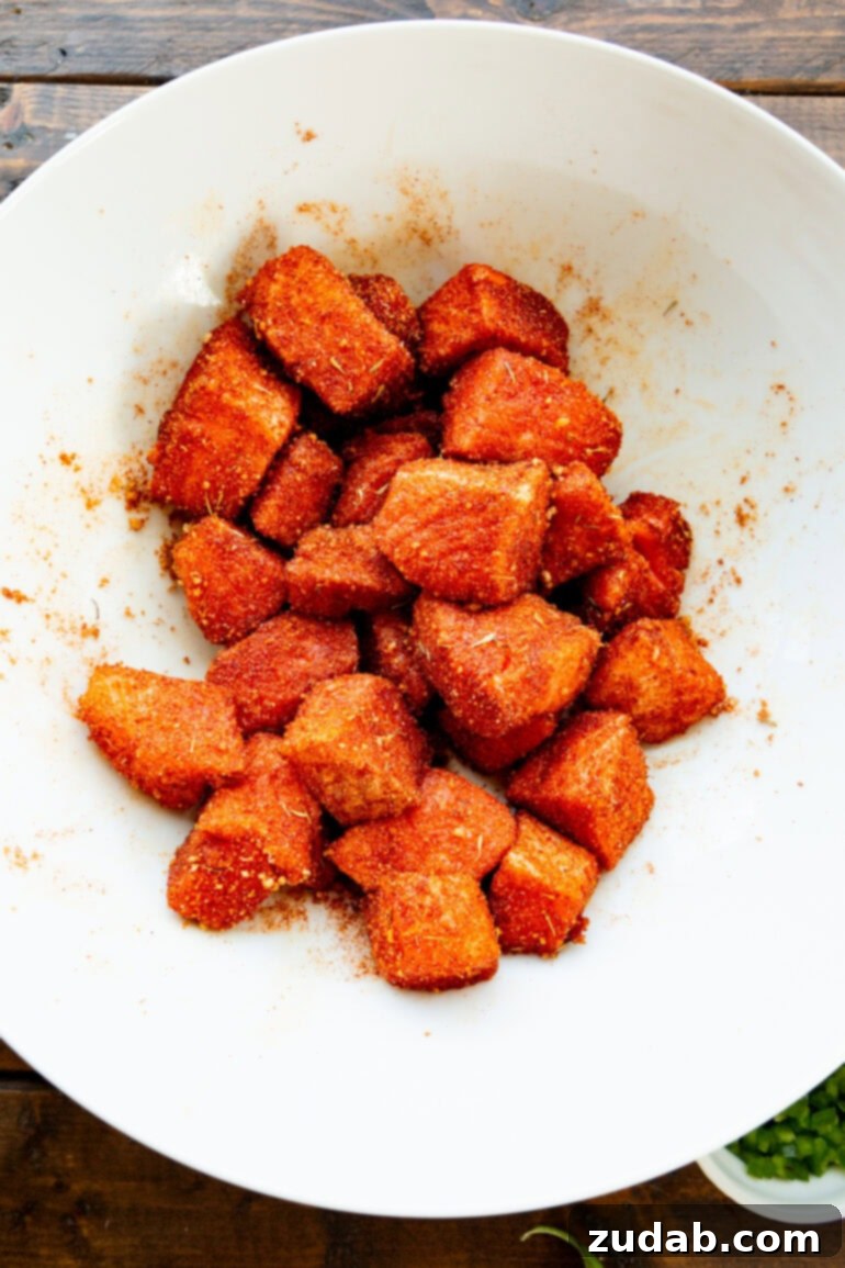 Golden Crispy 7-Minute Air Fryer Salmon Bites with Zesty Mango Salsa 6 A candid shot of raw salmon cubes coated evenly with a dry seasoning rub, resting in a white mixing bowl, ready for air frying.