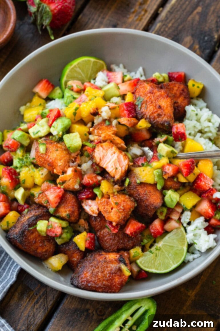 Golden Crispy 7-Minute Air Fryer Salmon Bites with Zesty Mango Salsa 9 A serving bowl filled with fluffy coconut rice, generously topped with crispy air fryer salmon bites and a fresh strawberry mango avocado salsa, creating a vibrant and wholesome meal.