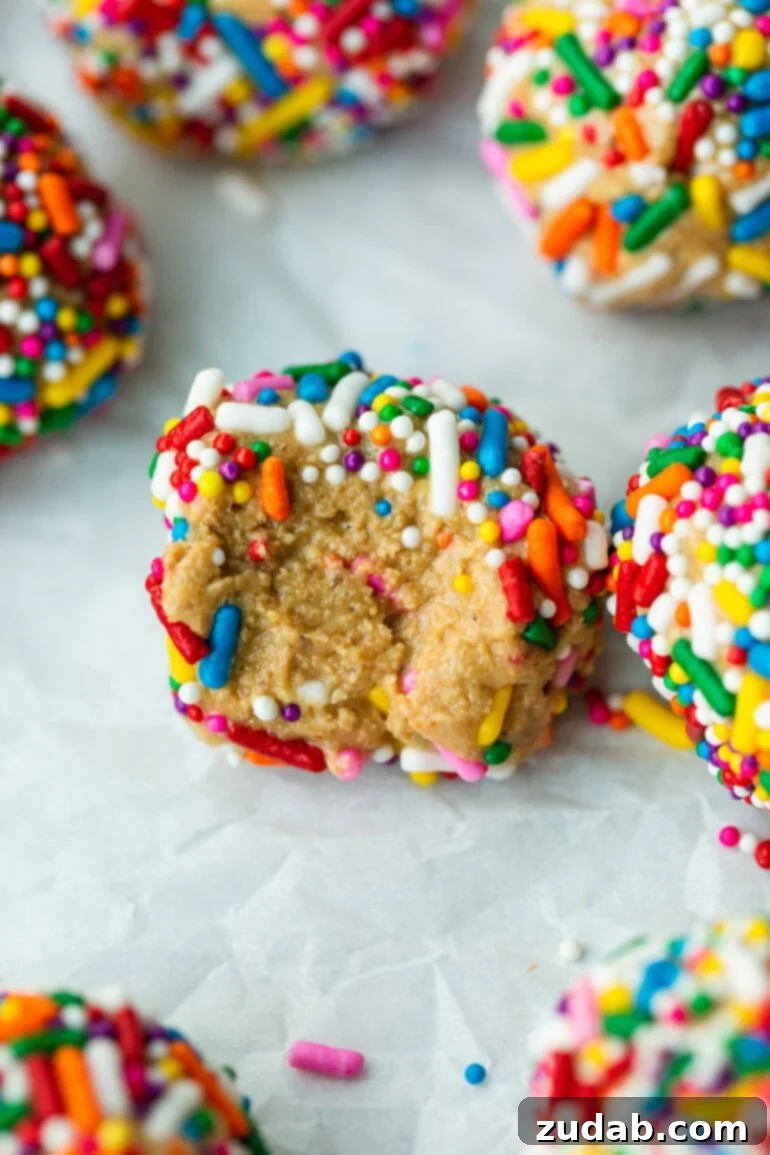 Funfetti Protein Poppers 2 a photo of several protein bites covered in rainbow sprinkles with one that has a bite taken out of it