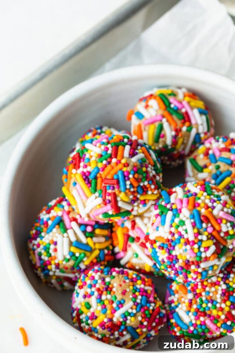 Funfetti Protein Poppers 7 a photo of a bowl of cake batter protein bites covered in rainbow sprinkles