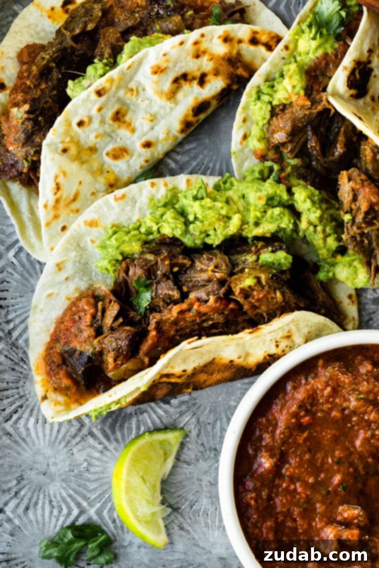 Deliciously Easy 5-Ingredient Shredded Beef Tacos 2 A beautifully arranged shredded beef taco on a flour tortilla, generously topped with fresh guacamole and a sprinkle of cilantro.