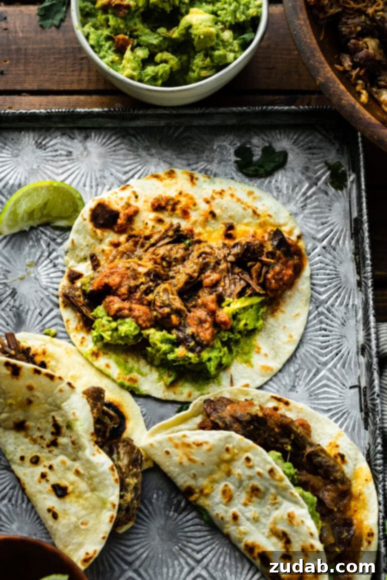 Deliciously Easy 5-Ingredient Shredded Beef Tacos 15 A rustic sheet pan displaying several neatly arranged shredded beef tacos on soft flour tortillas, highlighting their homemade appeal and delicious filling.