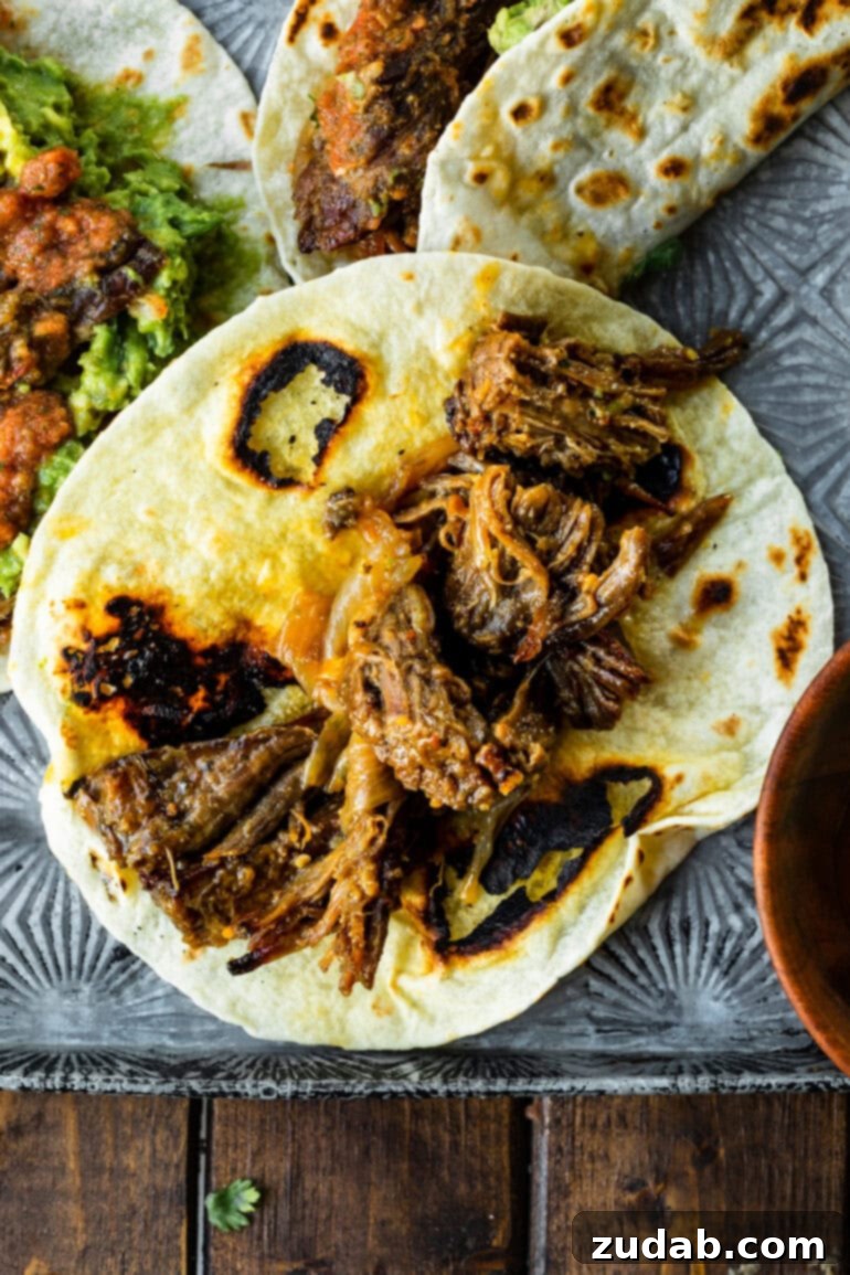 Deliciously Easy 5-Ingredient Shredded Beef Tacos 9 A soft flour tortilla generously piled with flavorful, juicy shredded beef, ready for toppings.